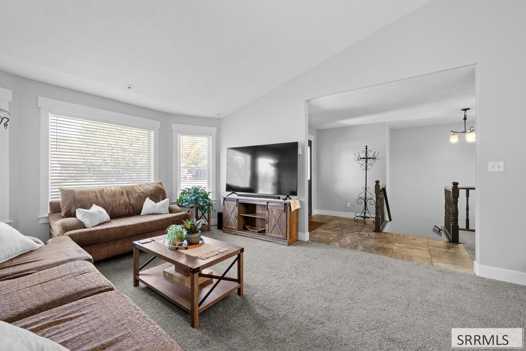 Living room with brown sofas, a television, large windows, and an open staircase.
