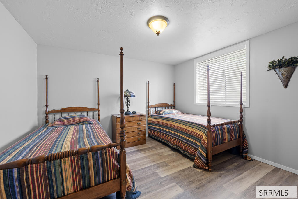 Bedroom with two wooden twin beds, colorful striped bedding, and a dresser between them.