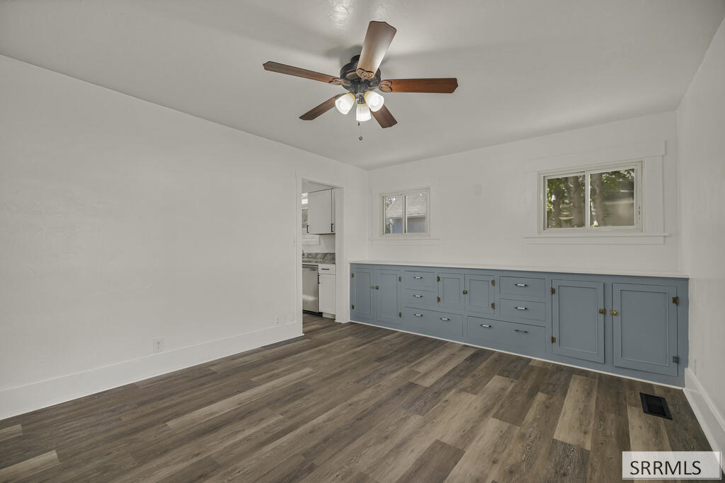 Dining area with blue-gray built-in cabinets, wood-look flooring, and a ceiling fan