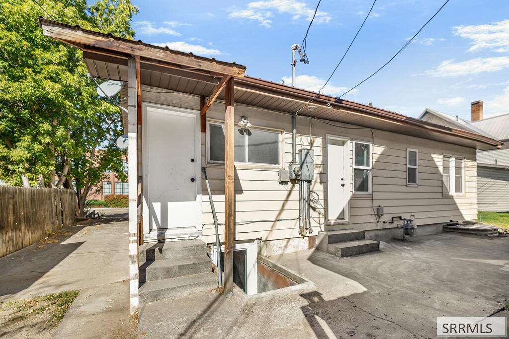 House exterior with a long covered awning, multiple entrances, and a basement stairwell.