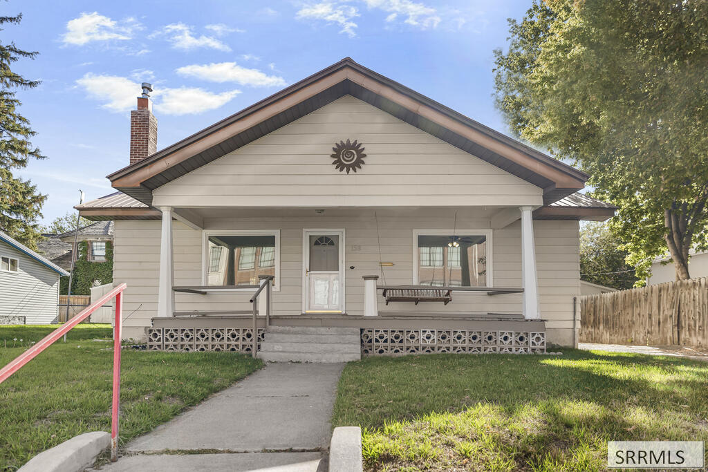 Light-gray house with a broad gabled roof, covered porch, and hanging swing.