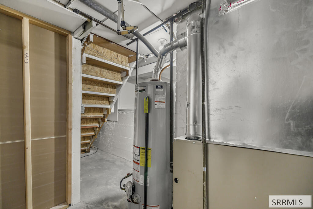 Basement utility area with a water heater, exposed ductwork, and open wooden stairs.