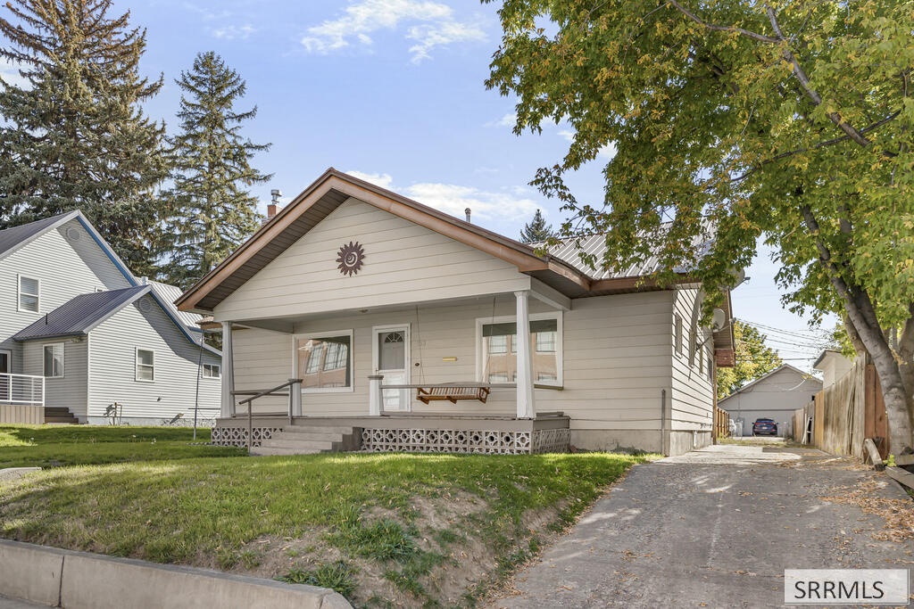 Light gray single-story house with a covered porch and driveway beside it.