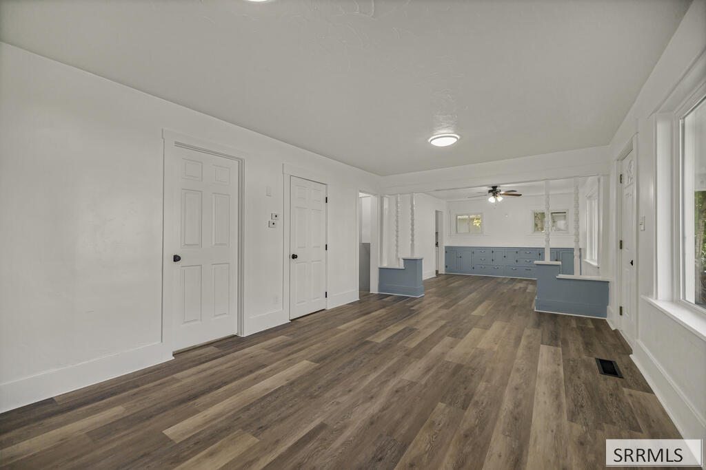 Empty open room with wood floors, large windows, and blue built-in cabinets.