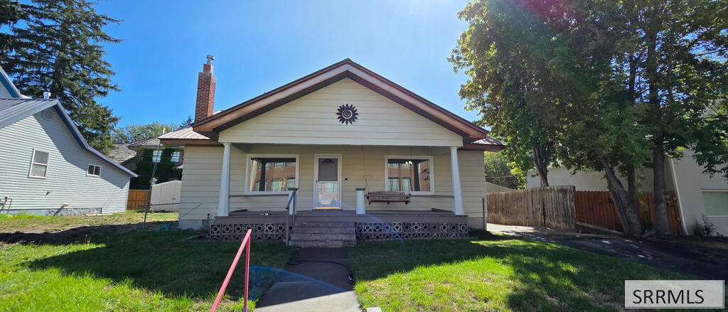 Single-story house with a covered front porch, sunburst gable decoration, and green lawn.