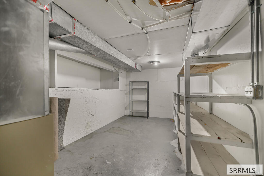 Unfinished basement storage room with metal shelving and exposed ductwork.