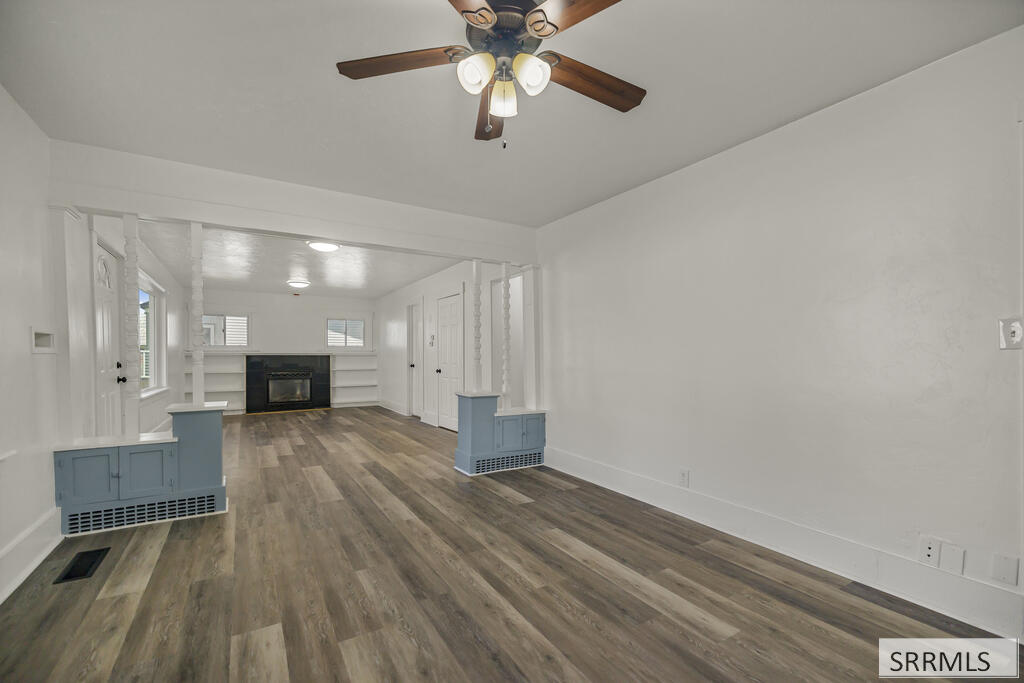 Vacant living room with a fireplace, built-in shelves, and wood-look flooring.