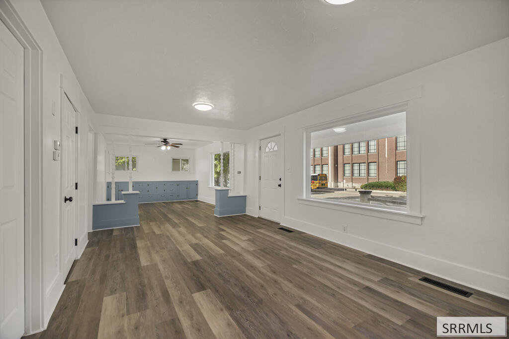 Vacant interior with blue built-in cabinetry, wood-look floors, and a large street-facing window.