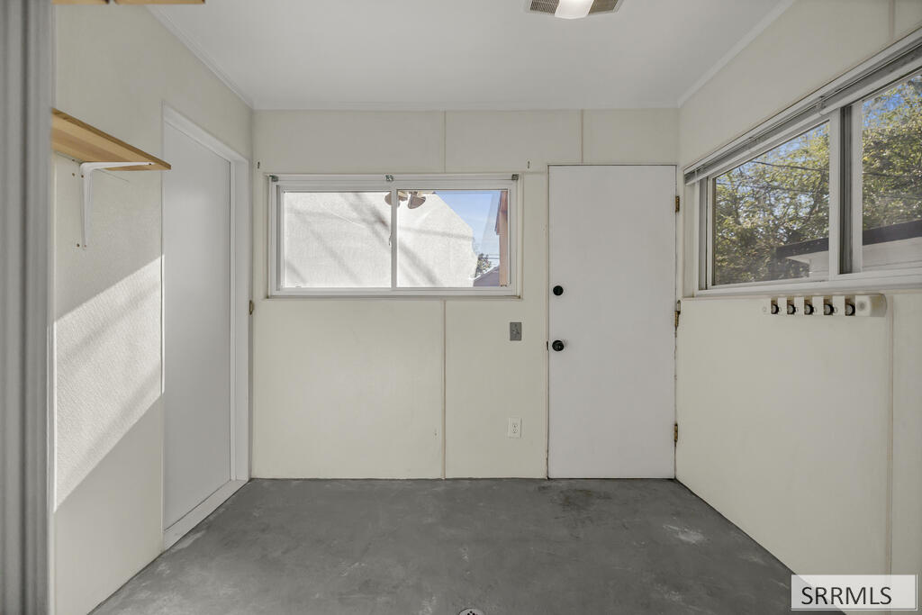 Empty utility room with a concrete floor, wall hooks, and windows.