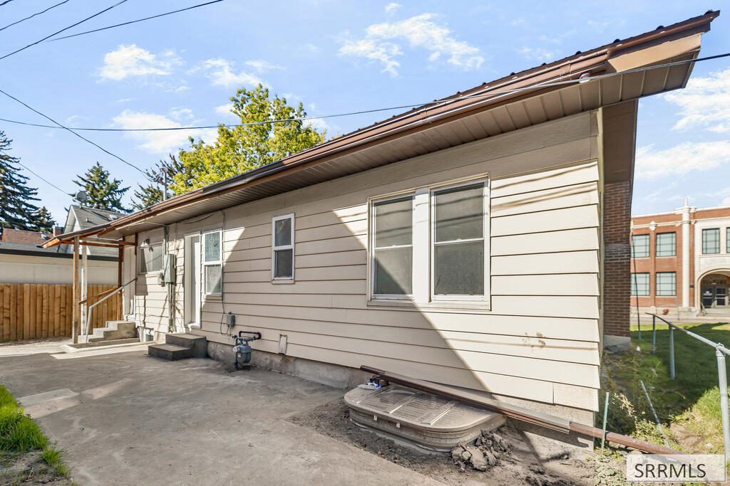 House side with light siding, several windows, and a concrete patio.