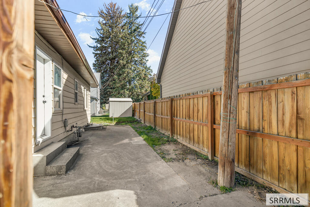 House side yard with a concrete walkway and wooden privacy fence.