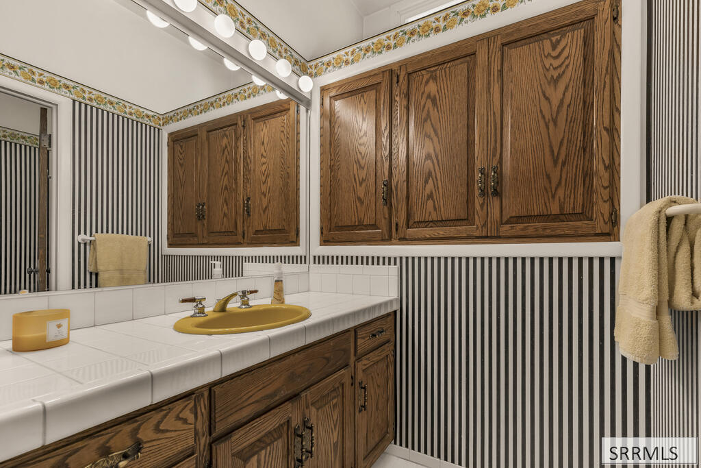 Bathroom vanity with a yellow sink, dark wood cabinets, and black-and-white striped wallpaper.