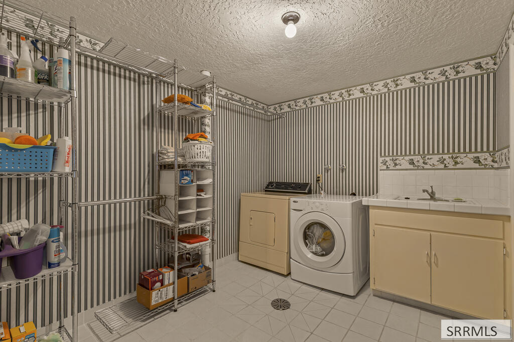 Laundry room with washer and dryer, a long utility sink, and stocked metal shelving.