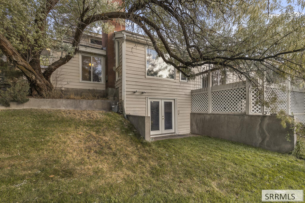 House exterior with a walkout lower level and lattice-covered deck beneath mature trees.