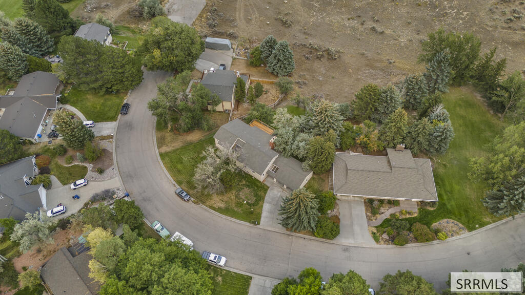 Aerial view of a home on a curved residential street, with landscaped yards and mature trees.