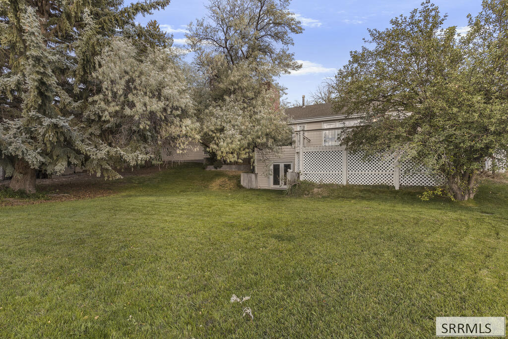 Grassy backyard with mature trees and a raised deck along the rear of the house.