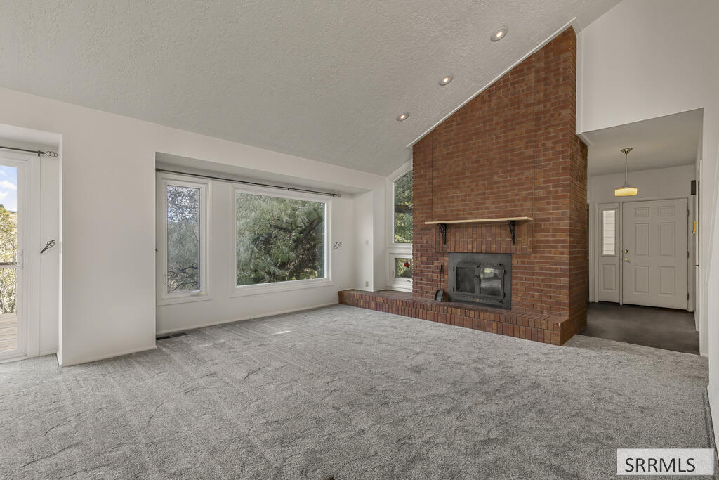 Vacant living room with a floor-to-ceiling brick fireplace and large windows.