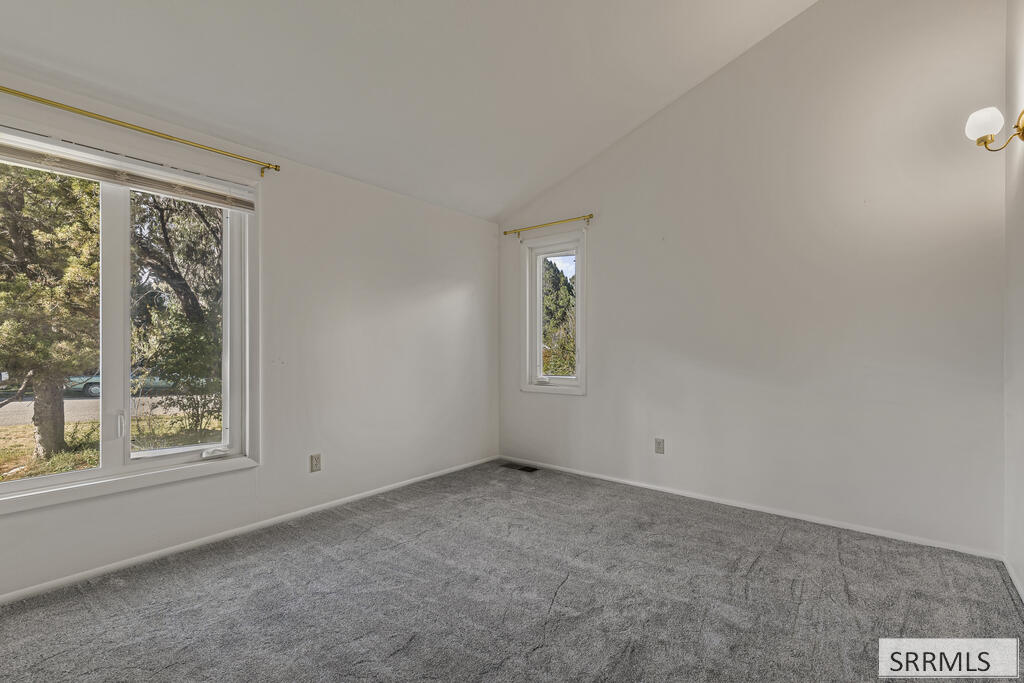 Vacant carpeted room with two windows and a sloped ceiling.