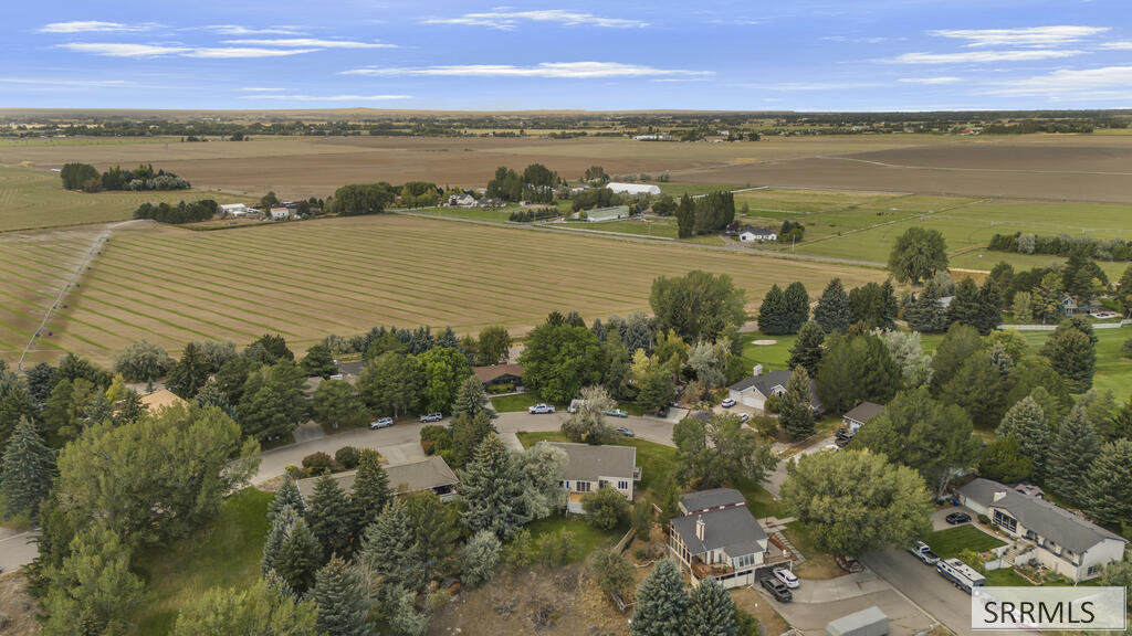 Aerial view of homes among mature trees, with expansive farmland beyond the neighborhood.