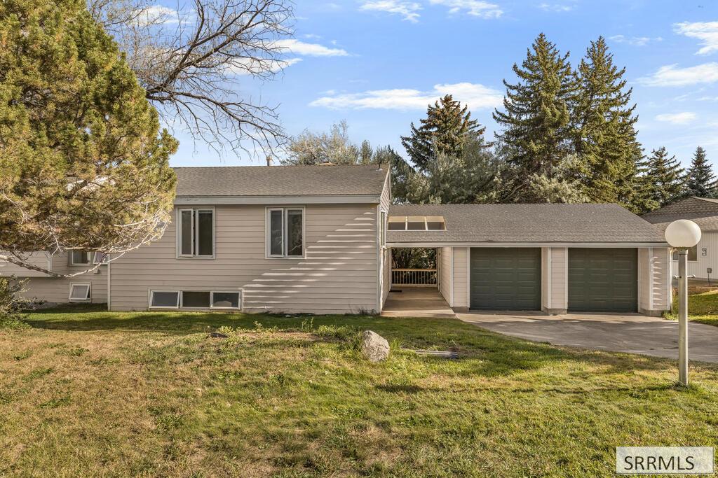Beige home with two garage doors, a covered entry passage, and a broad front lawn.