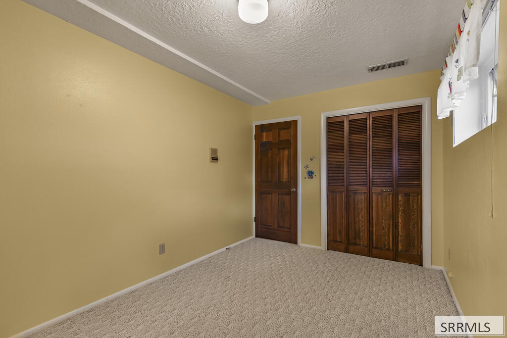 Unfurnished carpeted room with yellow walls and dark wood closet doors.