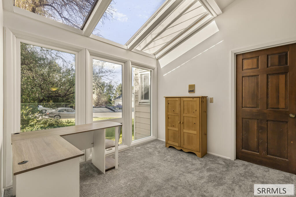 Bright office with skylights, large windows, a desk, and a wooden cabinet.