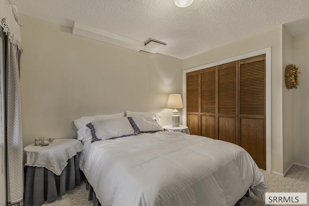 Furnished bedroom with a large bed and wooden louvered closet doors.