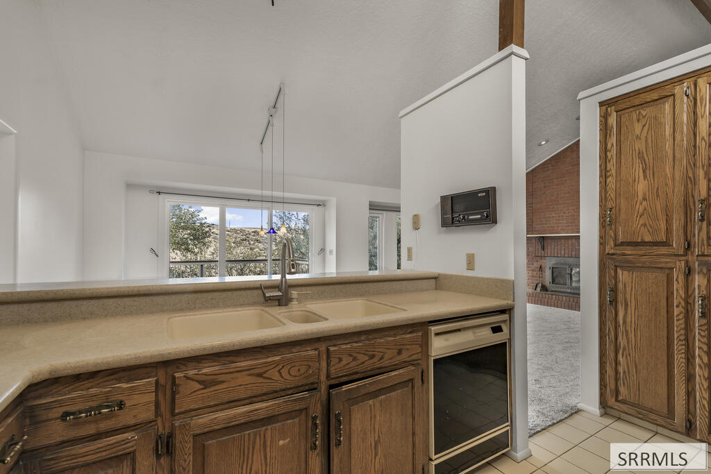 Kitchen with oak cabinets, a double sink, and a window overlooking trees.