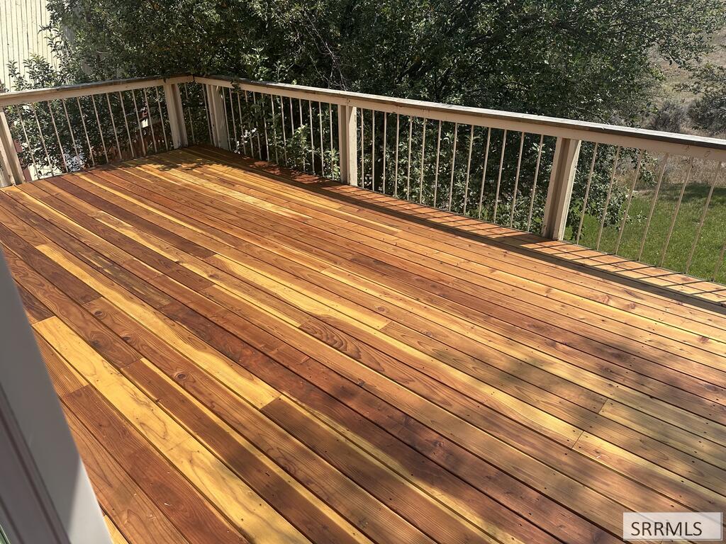 Wooden deck with fresh plank flooring and a light railing overlooking trees.