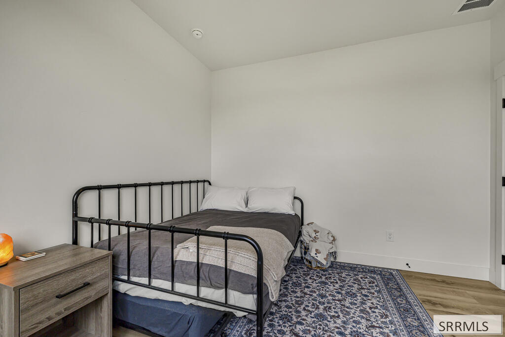 Bedroom with a black metal bed frame, gray bedding, and a blue patterned rug.