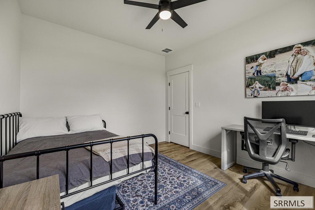 Bedroom with a black metal bed, blue patterned rug, and desk setup.