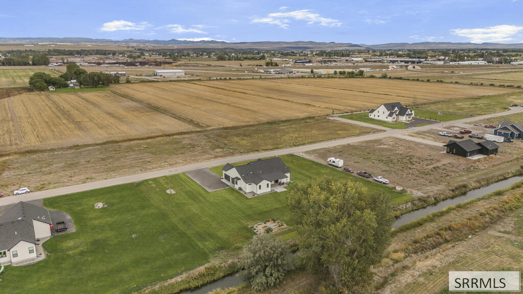 Aerial view of a white home on a broad lawn beside a canal and open farm fields.