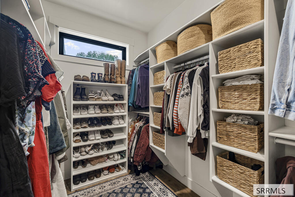 Walk-in closet with built-in shelving, woven baskets, hanging clothes, and neatly arranged shoes.