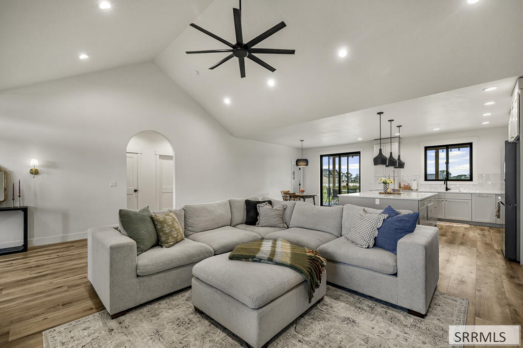 Open-plan living room with a gray sectional, patterned rug, and white kitchen island.