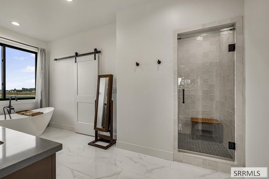 Modern bathroom with a freestanding tub, tiled glass shower, and sliding barn door.