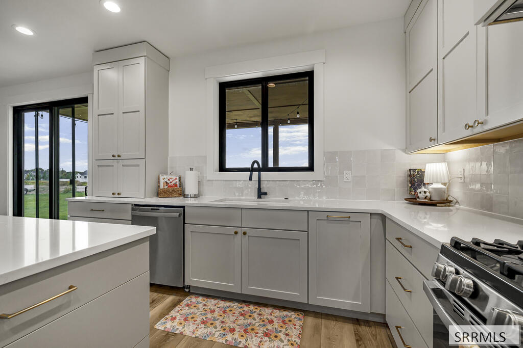 Modern gray-and-white kitchen with a window-side sink and sliding glass doors to a covered area.