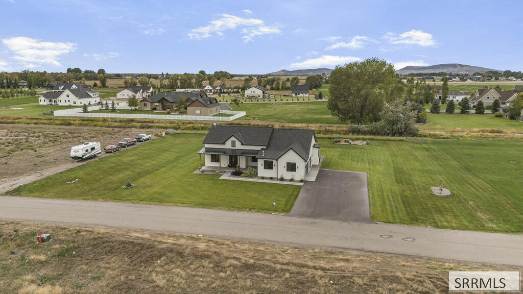 Aerial view of a single-story home with a broad lawn and long driveway.