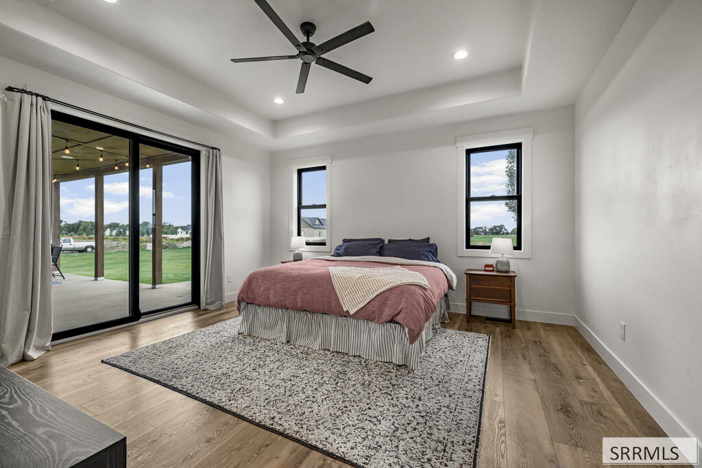 Bedroom with rose-colored bedding, a tray ceiling, and sliding glass doors opening to a covered patio.