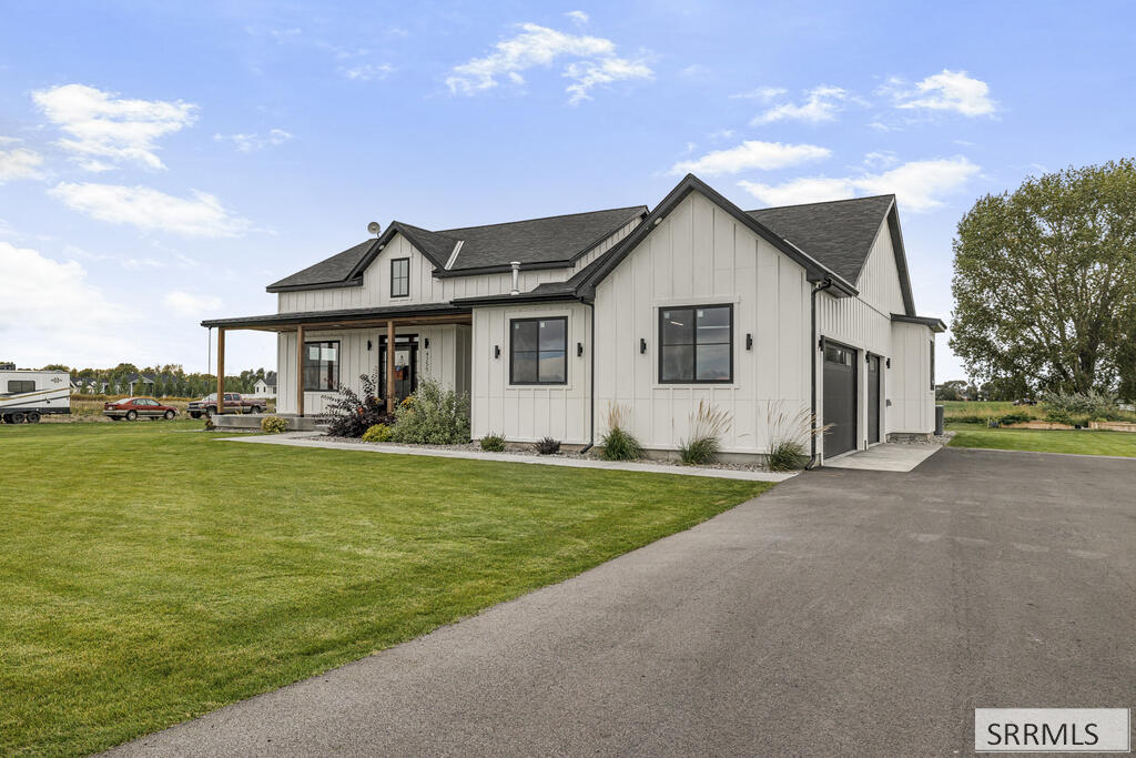 Modern farmhouse with a covered porch, attached garage, and broad paved driveway.