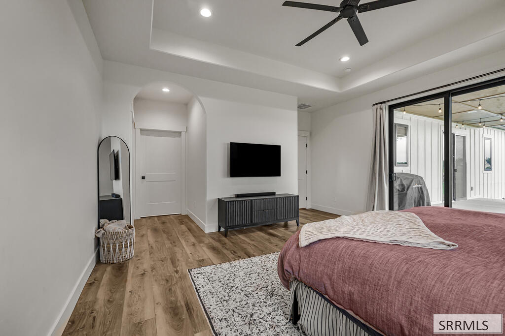 Bedroom with a mauve bed, tray ceiling, and sliding glass doors to a covered patio.