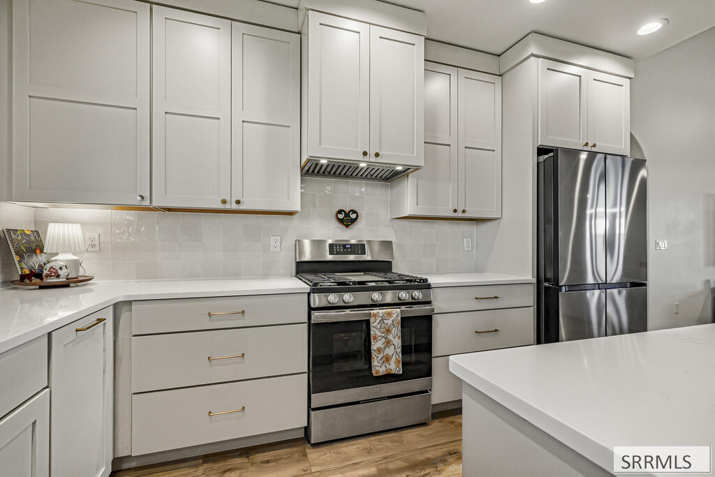 Kitchen with white shaker cabinets, stainless steel appliances, and a large white island.