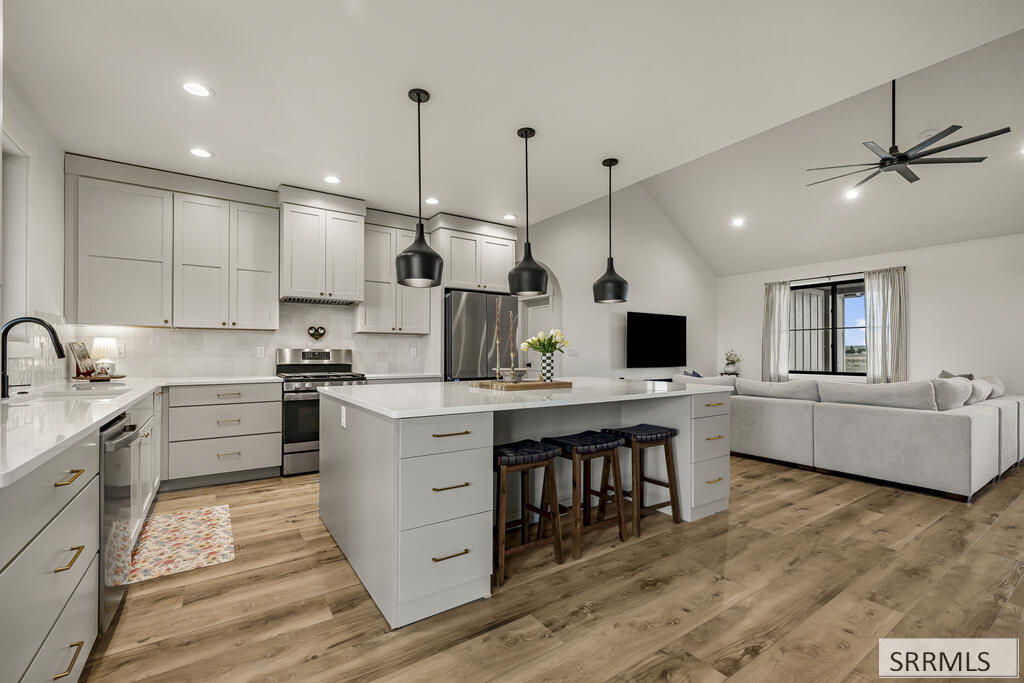 Open-plan kitchen with a large island and white cabinetry beside a furnished living area.