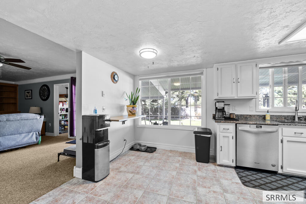 Kitchen with white cabinets and granite counters, opening to a living room beside a large patio-facing window.
