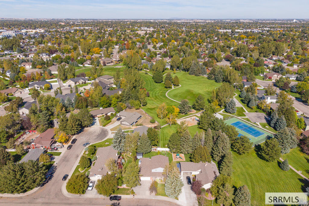 Aerial view of a tree-lined neighborhood surrounding a large park with walking paths and tennis courts.