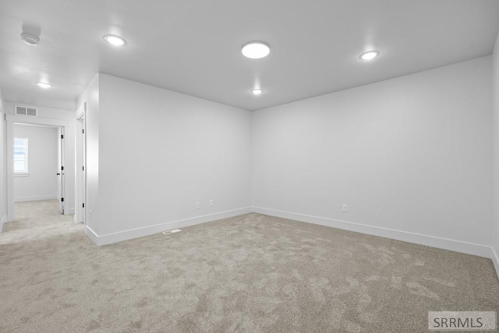 Vacant finished room with beige carpet, recessed lights, and an open doorway to the hall.
