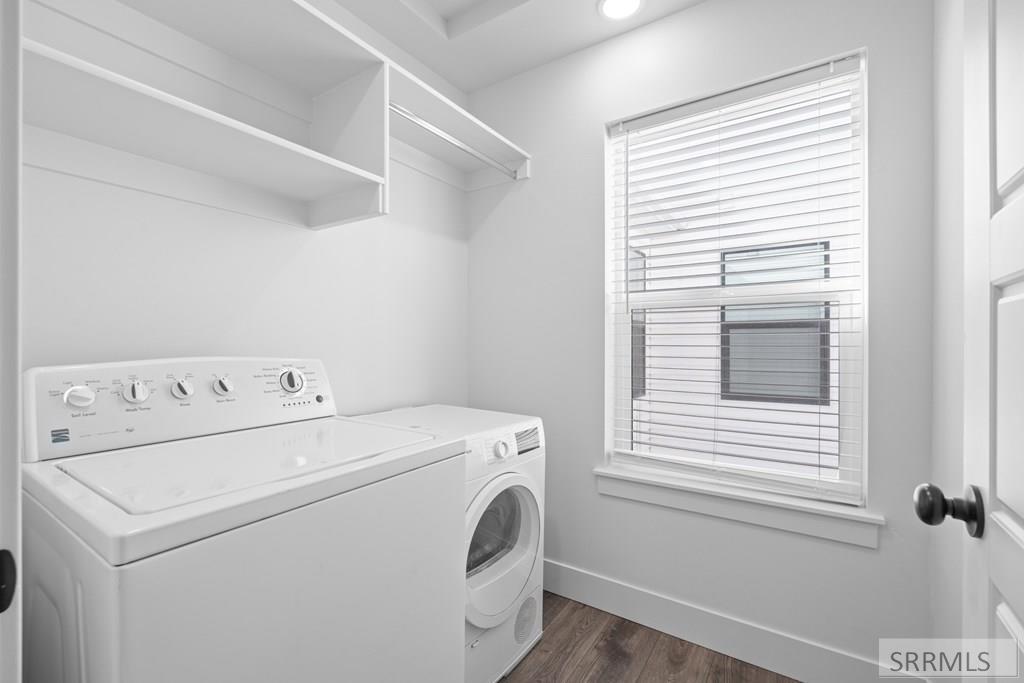 Laundry room with white washer and dryer, open overhead shelves, and a window with blinds.