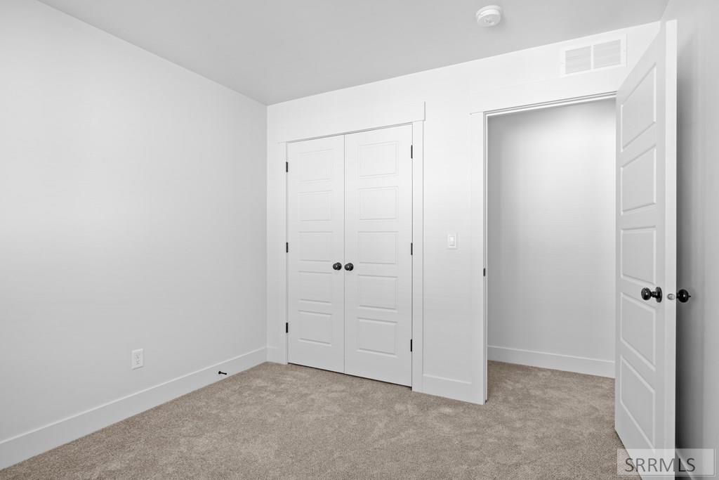 Empty carpeted bedroom with double closet doors and an open doorway.
