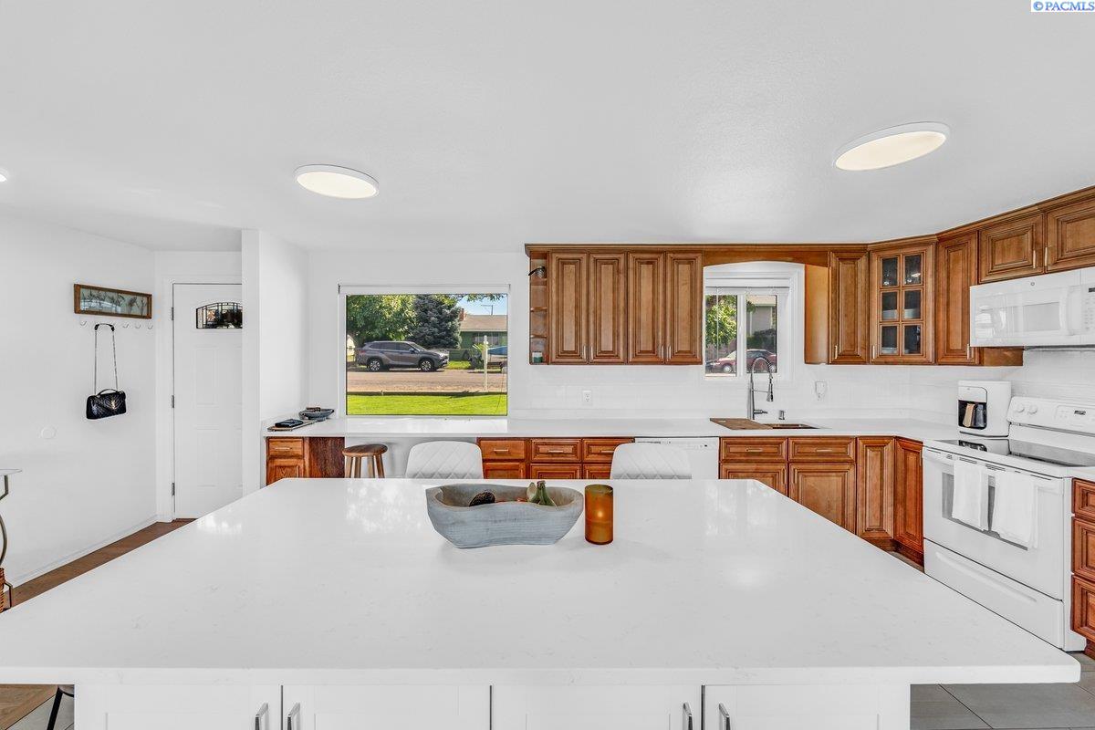 Bright kitchen with warm wood cabinets, a large white island, and windows overlooking the street.