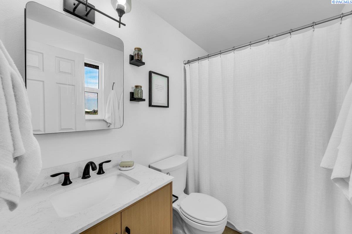 Bathroom with a marble-look vanity, black faucet, wood cabinetry, and white shower curtain.