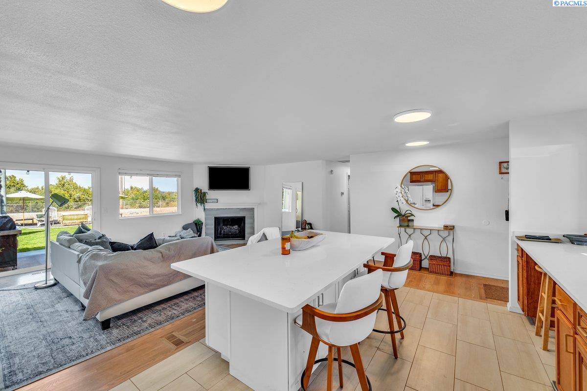 Open kitchen and living room with a large island, gray sectional, fireplace, and sliding doors to the backyard.